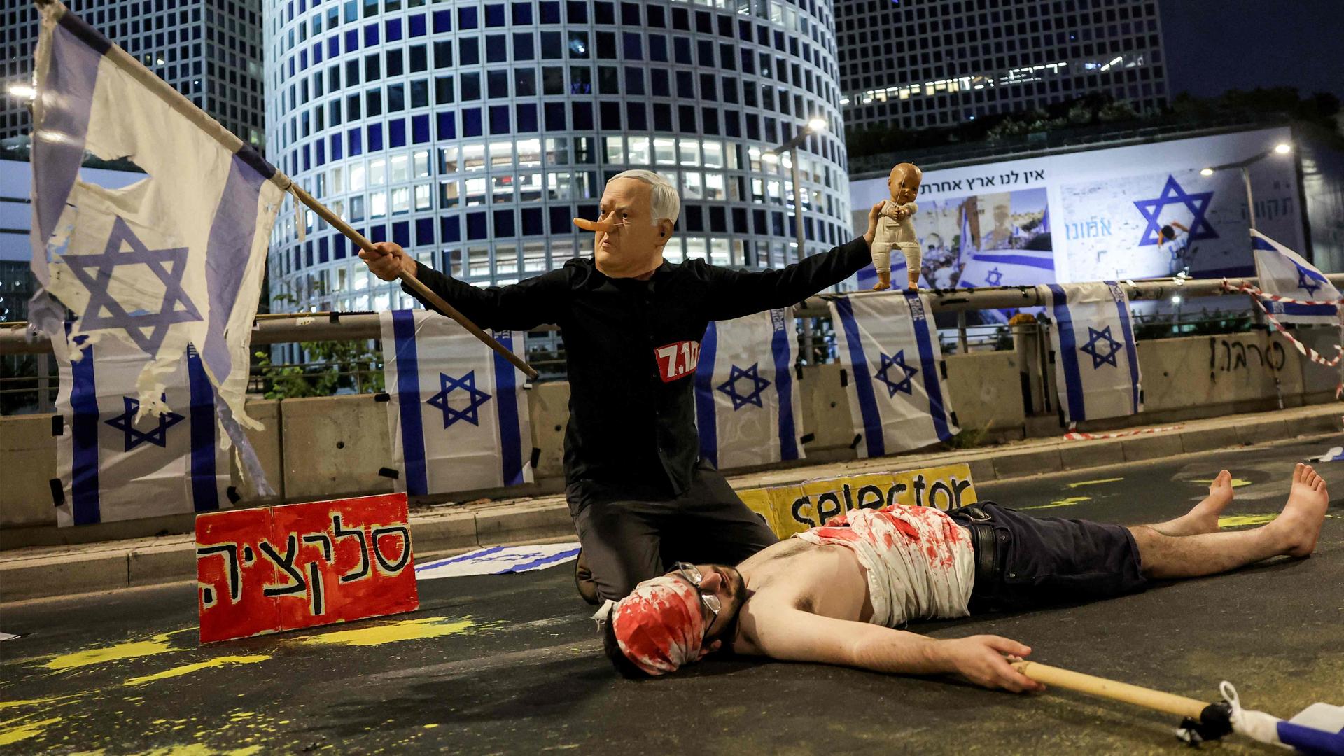 Een demonstrant verkleed als premier Netanyahu, met een lange neus als Pinokkio,  buigt zich bij een protest in Tel Aviv over een ’gijzelaar’. 