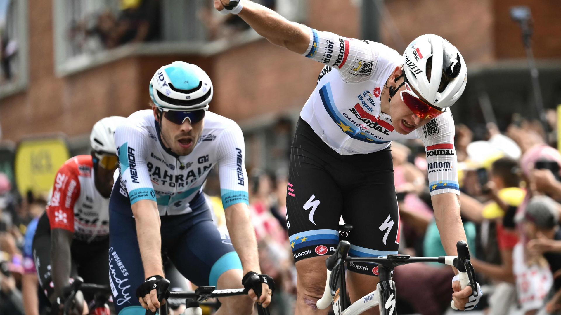 Tim Merlier drukt zijn wiel als eerste over de finish. 
