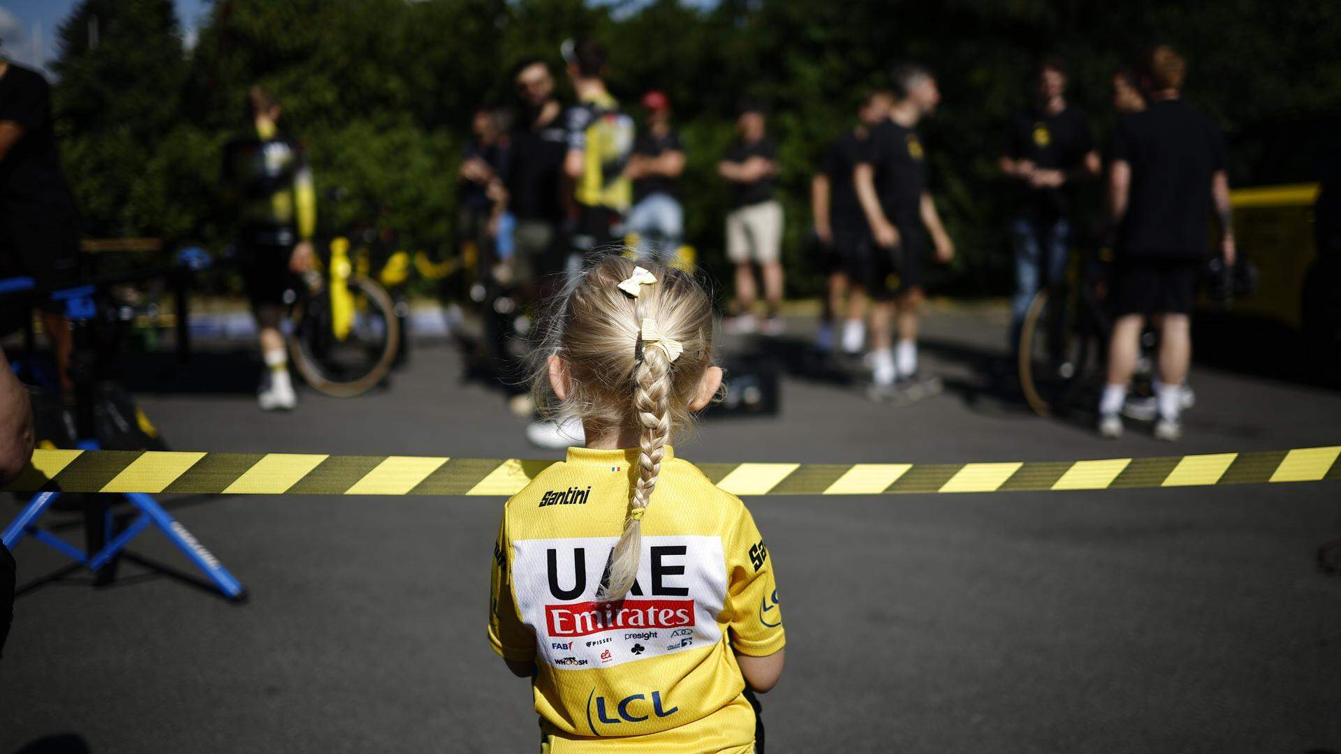 Een jonge fan van UAE Emirates kijkt naar de ploeg van  Visma-Lease a Bike.
