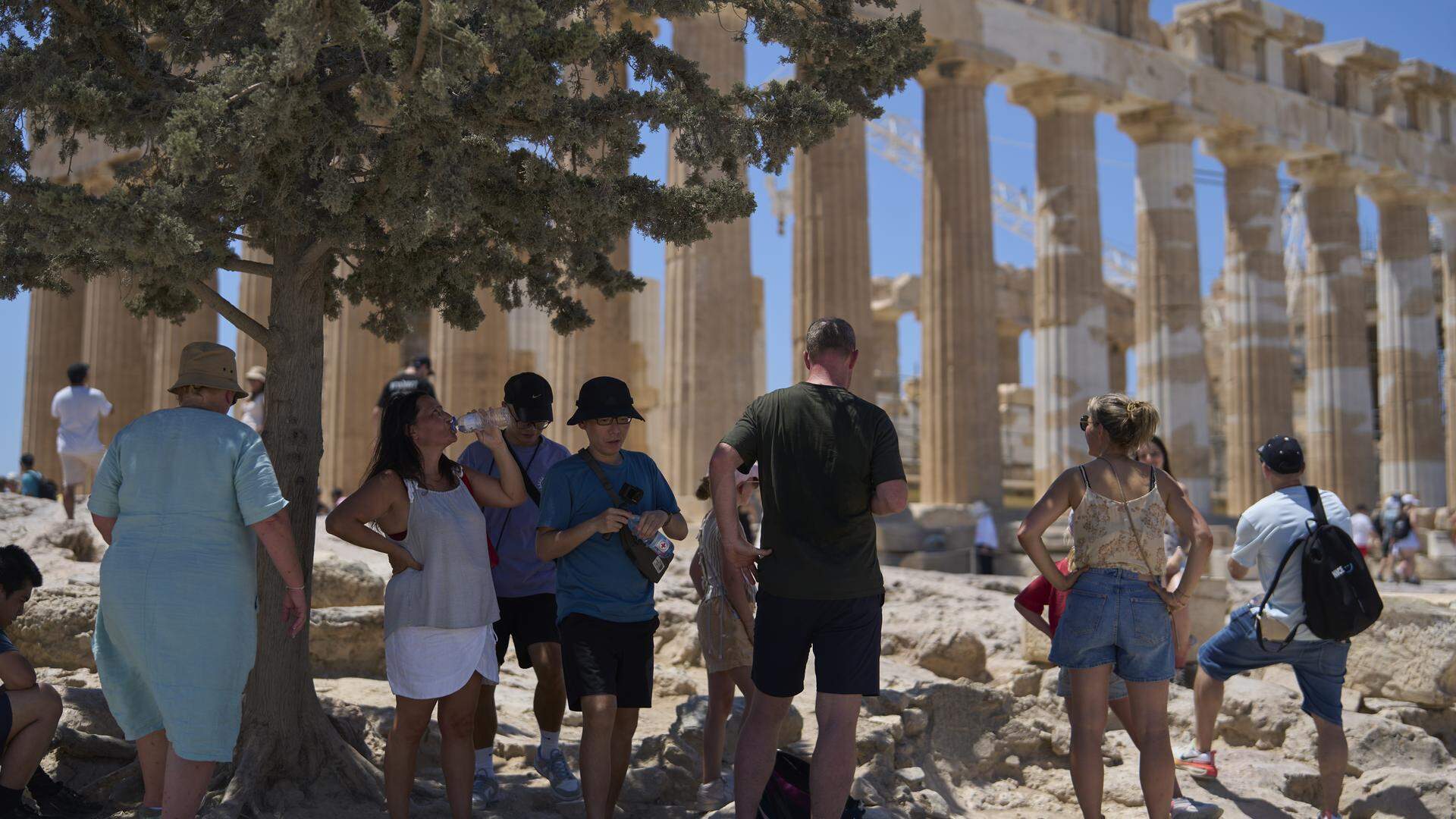 Toeristen zoeken de verkoeling op bij de Akropolis in Athene. 