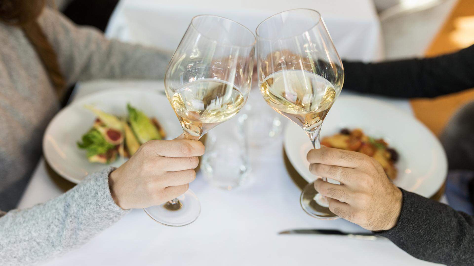 Close-up of couple clinking wine glasses in a restaurant