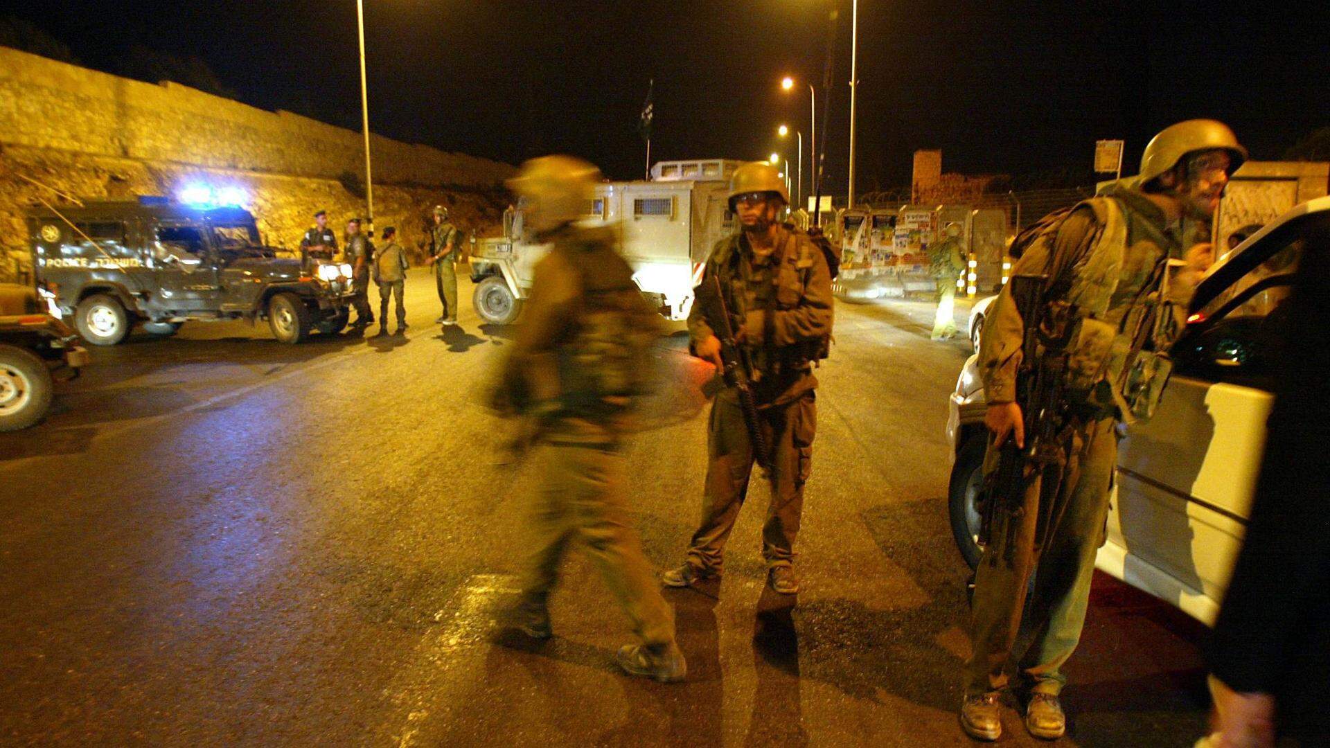 Israeli soldiers install a checkpoint in southern Jerusalem 04 August 2003. Security was increased in the zone after a family car was attacked by the Palestinian militant Al-Aqsa Martyrs Brigades at the Walajeh Checkpoint near Har Gilo, between Gush Etzion and southern Jerusalem. One Israeli woman and her three children were wounded in the attack.  
PEDRO UGARTE / AFP